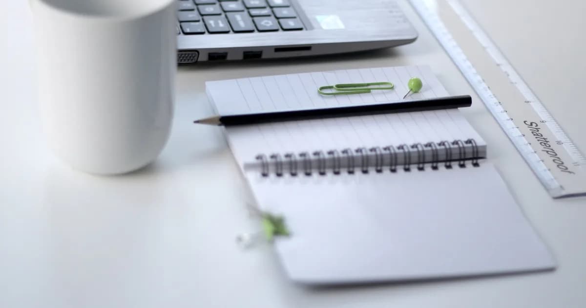 Laptop, notebook, and ruler on a desk while optimizing resume keywords for a specific job description.