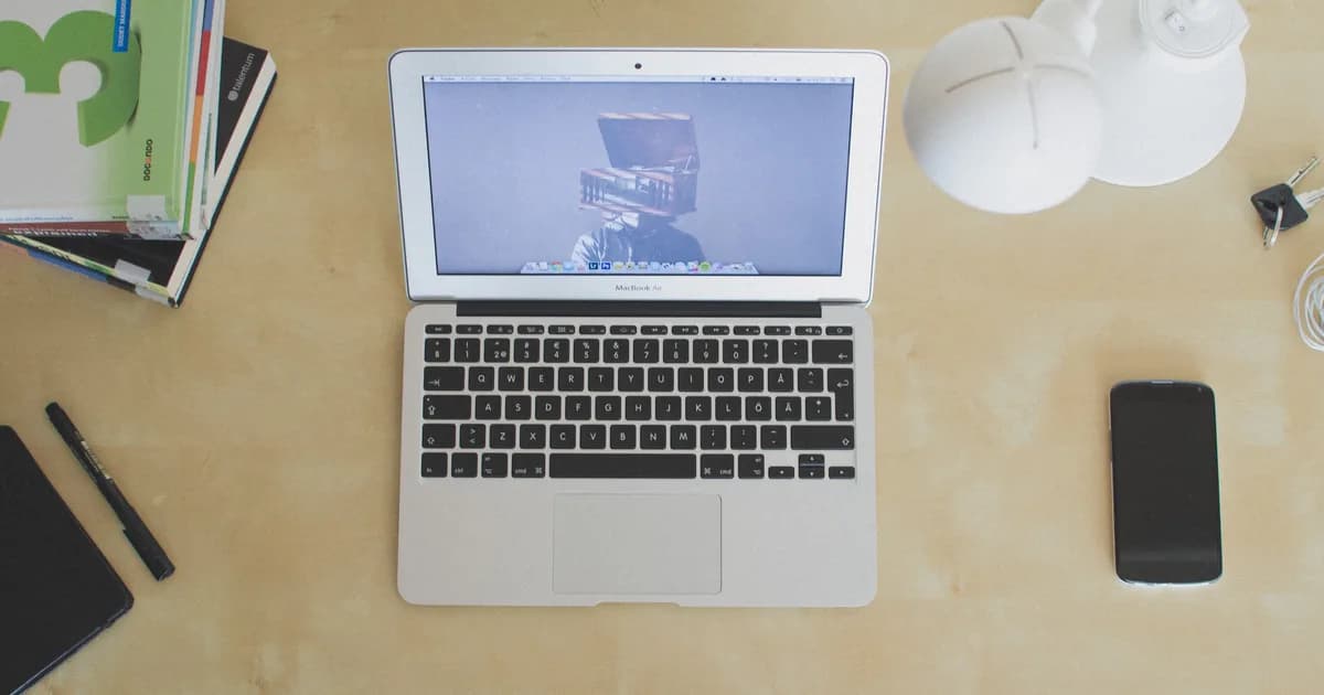 Laptop, notebook, and coffee on a desk during a resume tailoring session.